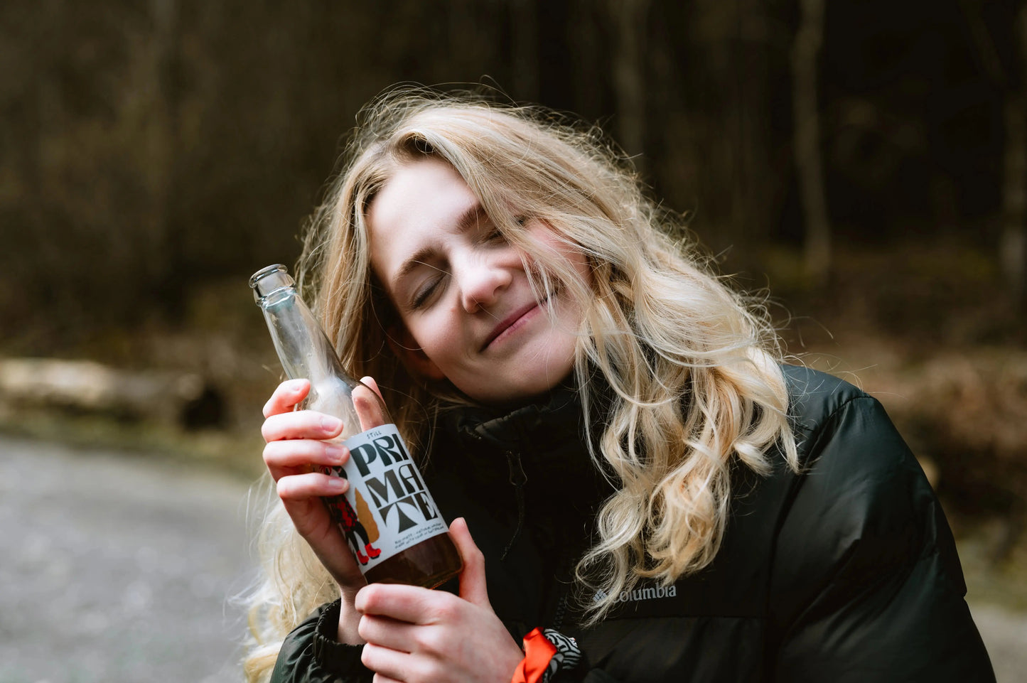 Eine Frau hält eine Bio-Still Flasche von Pri Mate in die Kamera.